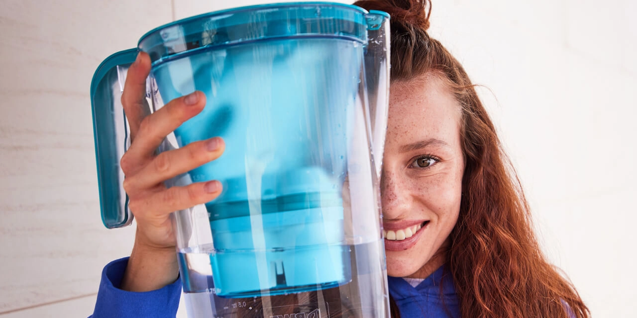 Femme présentant un filtre à eau de table